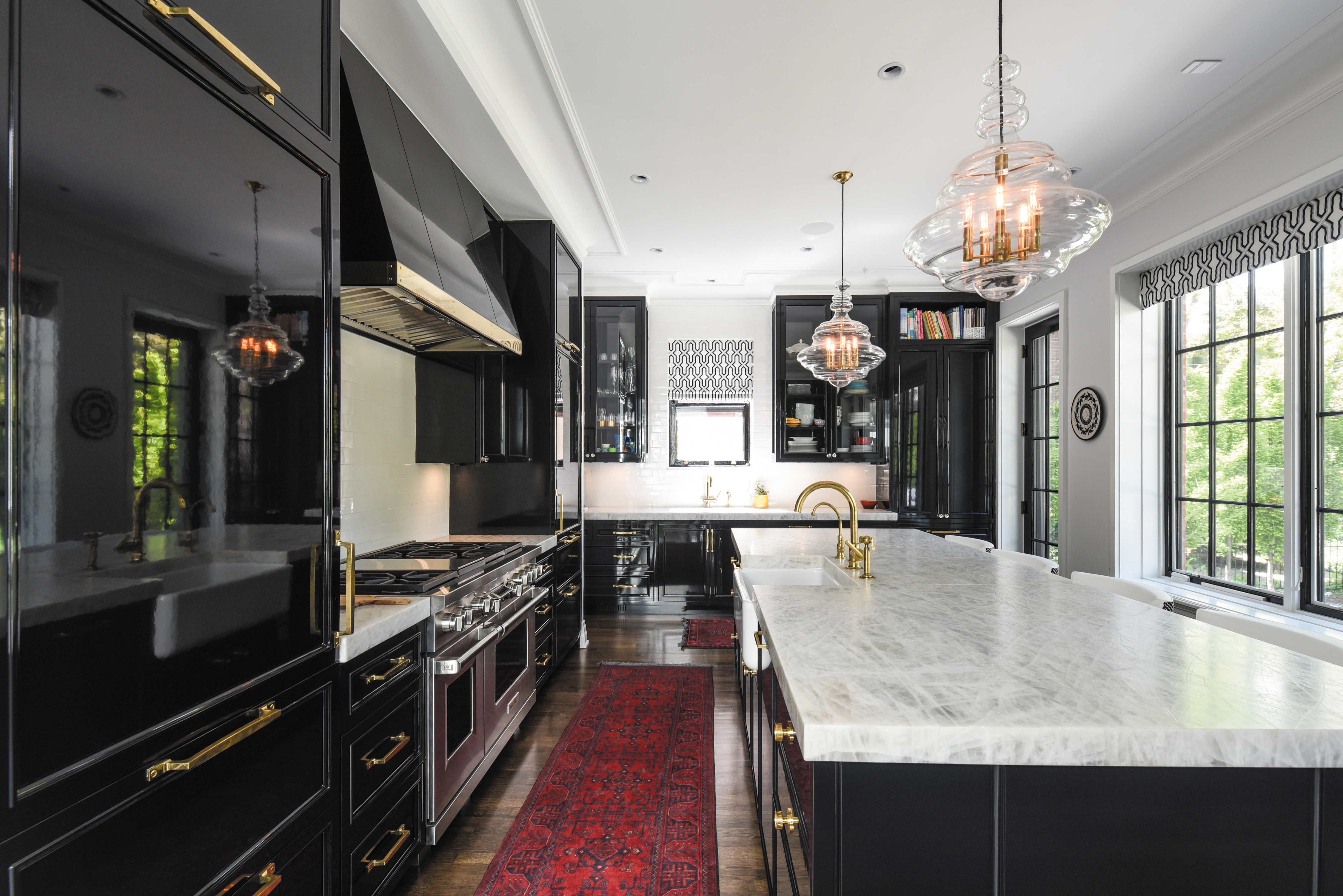 An elegant kitchen brings together Shaker-style, high-gloss painted cabinetry and paneled appliances, combined with brass trim details.
